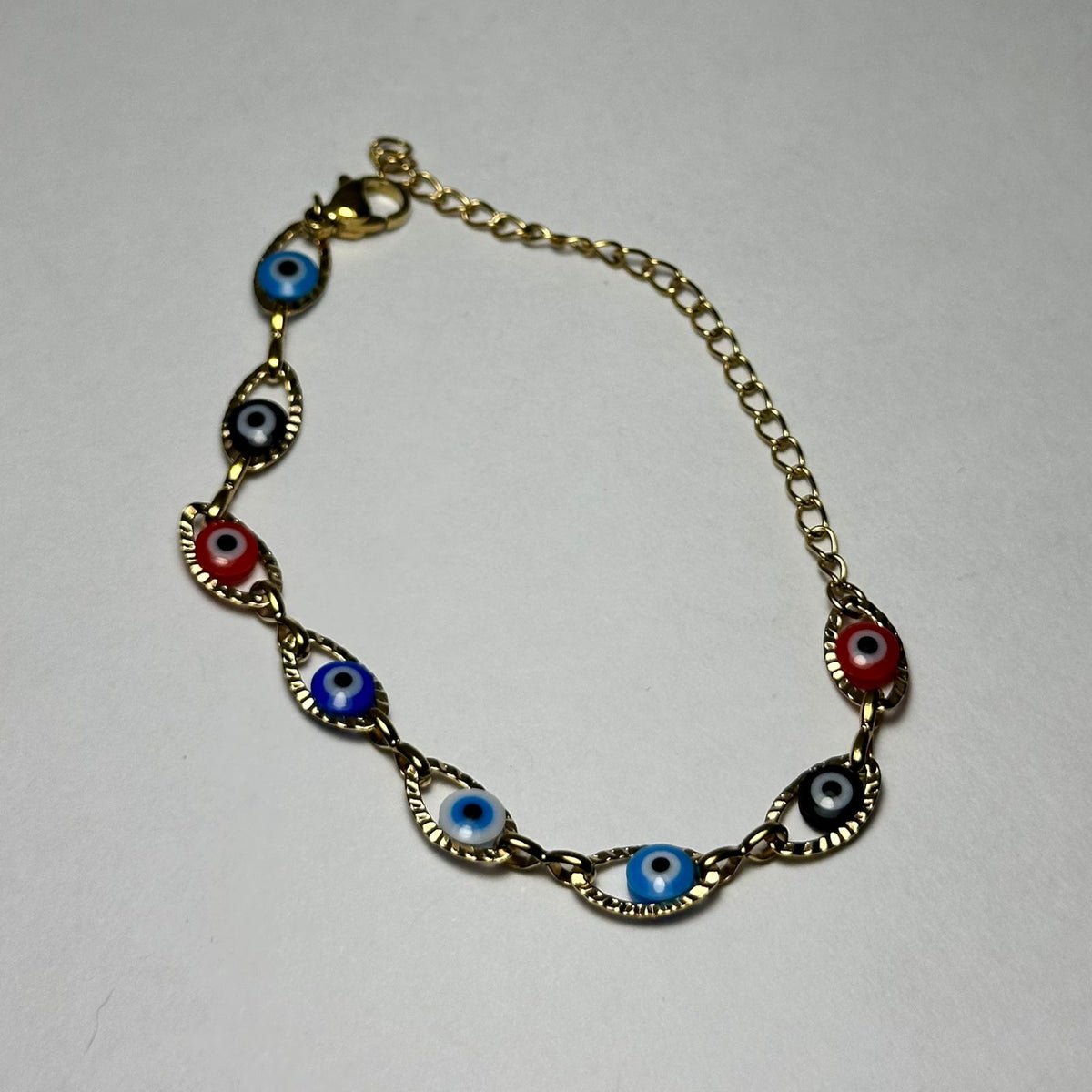 Pulsera simple ojitos de colores variados.oro